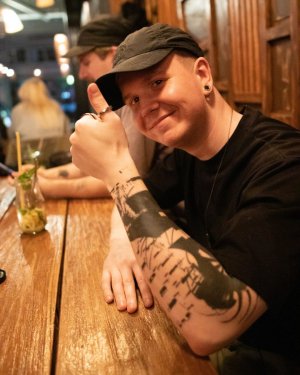 Techwear.Germany aka Janek sitting in a restaurant like me with thumbs up smiling into the camera in an all black outfit