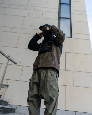 Techwear.Germany aka Janek next to a big futuristic building in Copenhagen in a techwear outfit consisting of North Face Cap, ACRONYM NG4, ACRONYM J1WTS-GT techwear jacket, ACRONYM P30A-DS techwear pants and Asics Gel Nimbus9 shoes