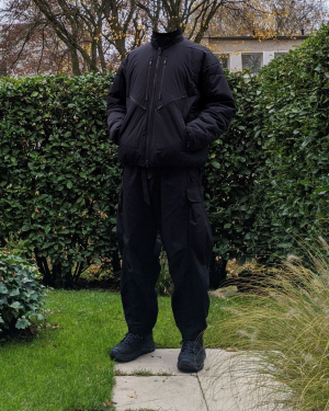 One person standing in a garden with ACRONYM J91 Techwear jacket, Nilmance Reversible Techwear Cargo and Hoka Tor Low Techwear shoes